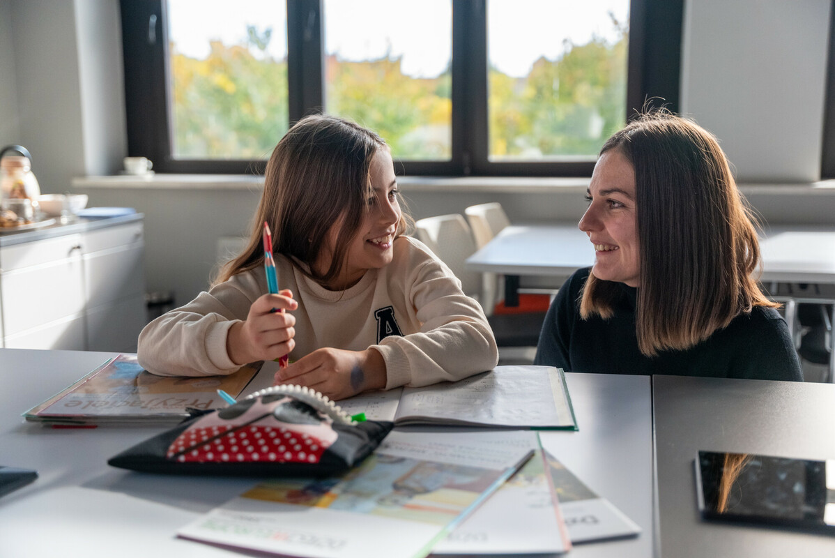 Viktoriia,* a Ukrainian psychologist and teacher, helps to Sophiia,* a refugee from Ukraine at a digital learning centre in a library in southern Poland funded by Save the Children with DEC funds. Image: Paul Wu/DEC