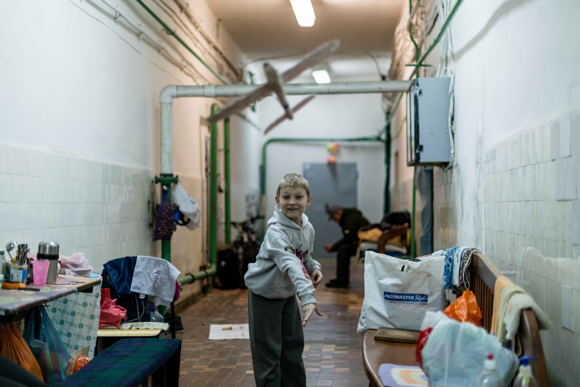 Kolia*, plays with a toy aeroplane in an underground shelter provided with a generator as well as food and other items by Depaul International with funding from CAFOD and Plan International. Image: Maciek Musialek/DEC. 